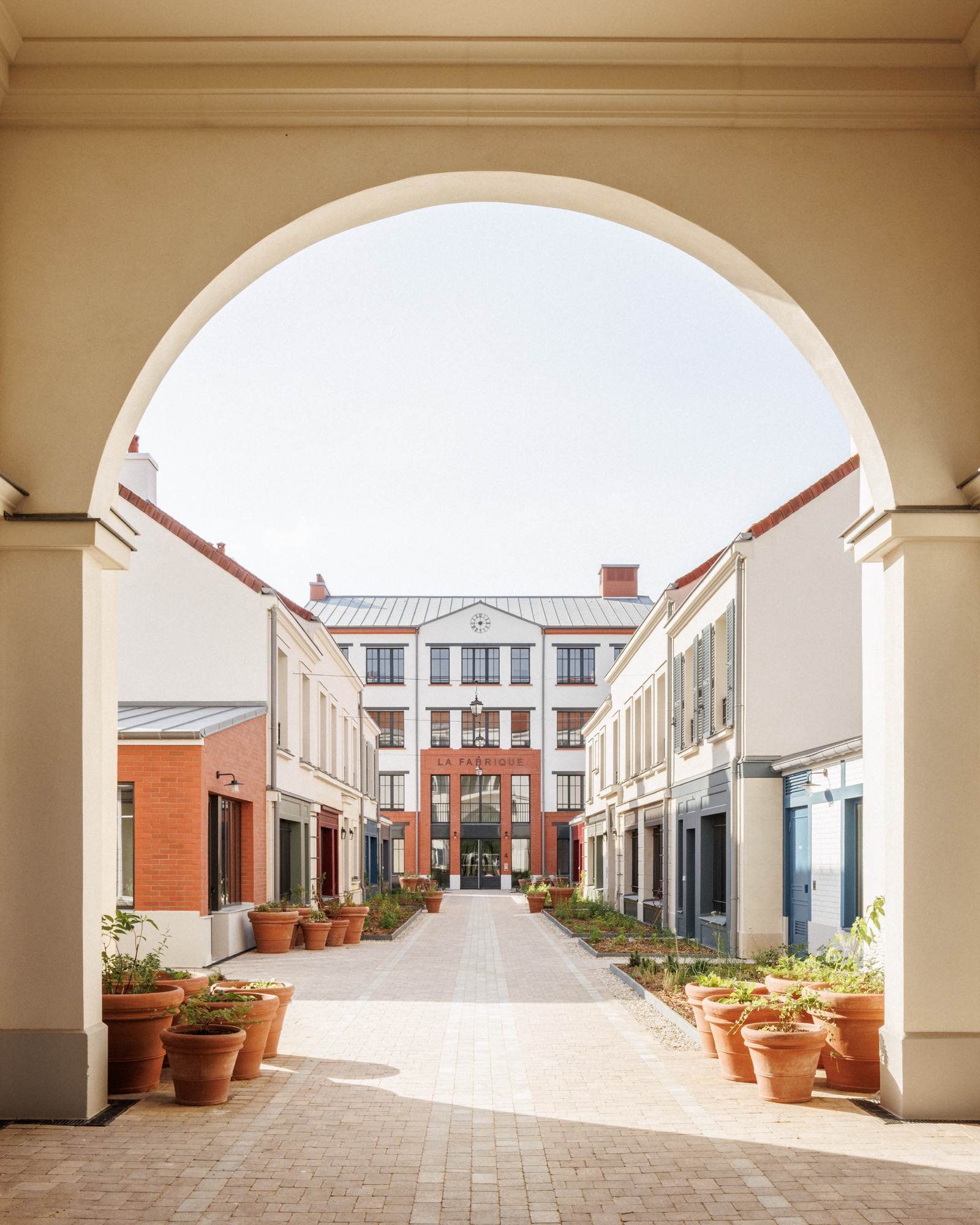 Vue de la Cour des Artisans depuis le porche double hauteur menant au bâtiment « La Fabrique » dans un ensemble de 47 logements sociaux à Serris (Seine-et-Marne), conçu par Cussac Architectes.
